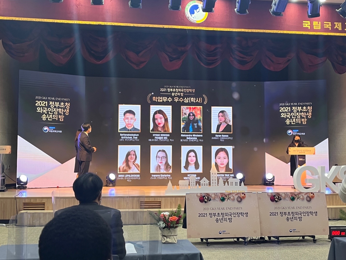 Stage screen at the 2021 GKS Year-End Party showing academic-achievement award recipients, including Xiyana Figuera.