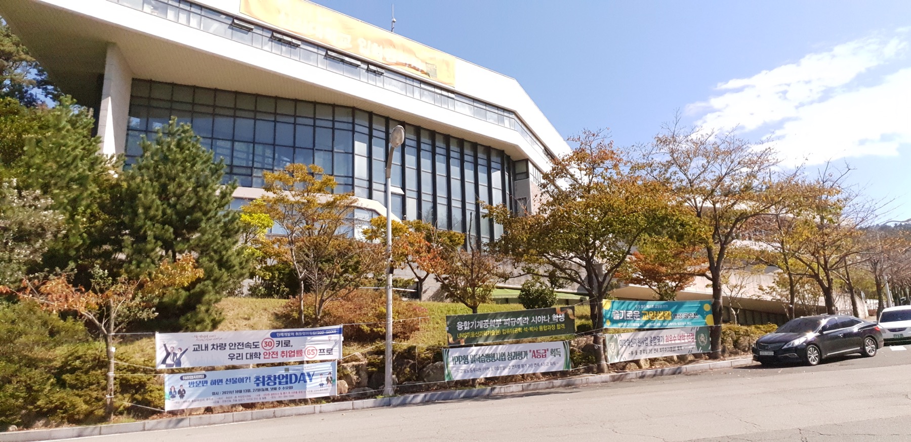 Wide campus view of Silla University banners, including a banner recognizing Xiyana Figuera's UNIST graduate-school admission.